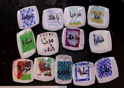Mosaic coasters and sun-catchers displaying Arabic hospitality expressions.