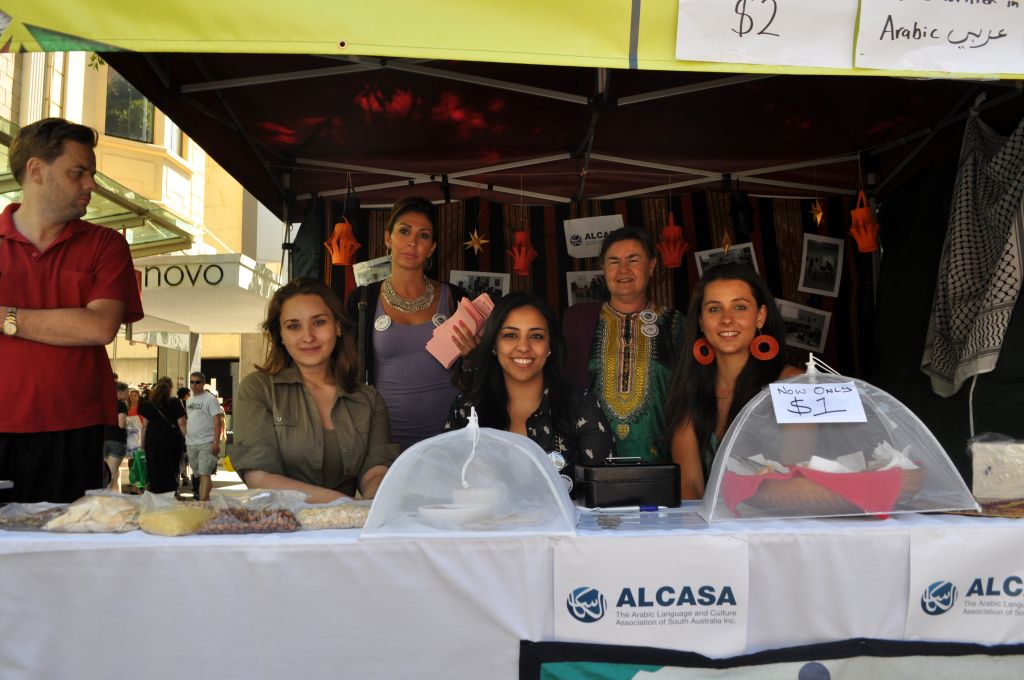 a group of smiling people sitting behind a table in a stall